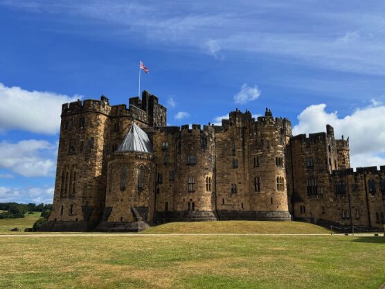 Alnwick Castle seen head-on from the south, its curtain wall and Barbican above the Pastures